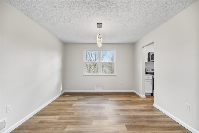 spare room featuring a textured ceiling and light wood-type flooring