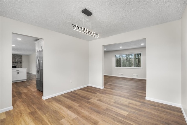 spare room featuring wood-type flooring and a textured ceiling