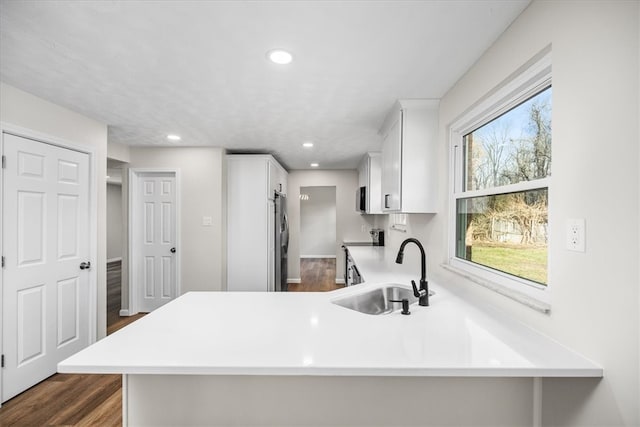 kitchen featuring kitchen peninsula, stainless steel appliances, sink, and dark hardwood / wood-style floors