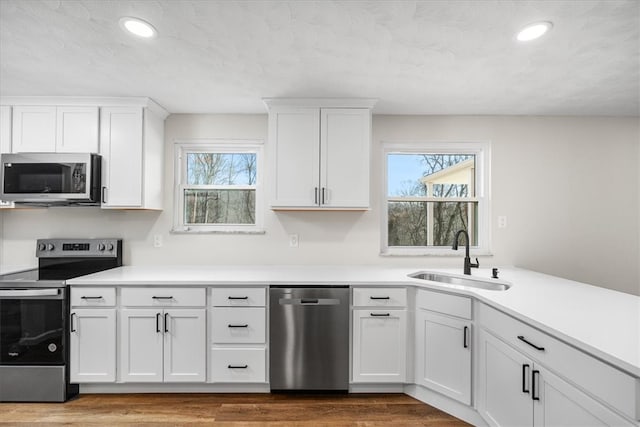 kitchen featuring white cabinets, wood-type flooring, sink, and appliances with stainless steel finishes