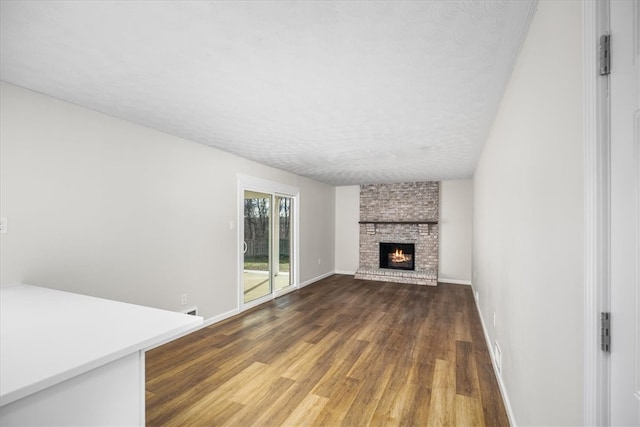 unfurnished living room featuring dark wood-type flooring, a fireplace, and a textured ceiling