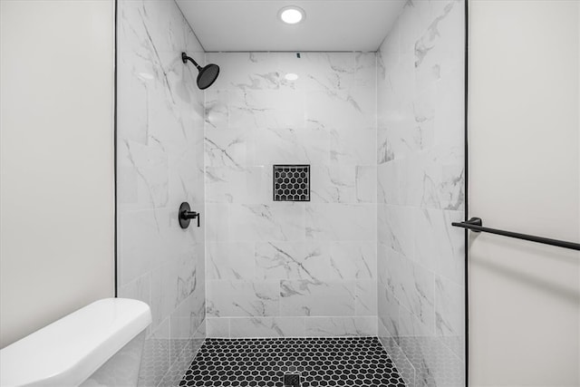 bathroom featuring a tile shower and toilet