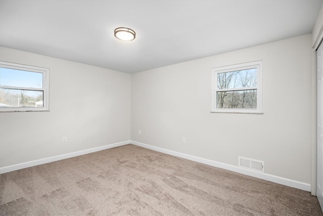 spare room with plenty of natural light and light colored carpet