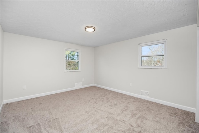 carpeted empty room featuring a textured ceiling