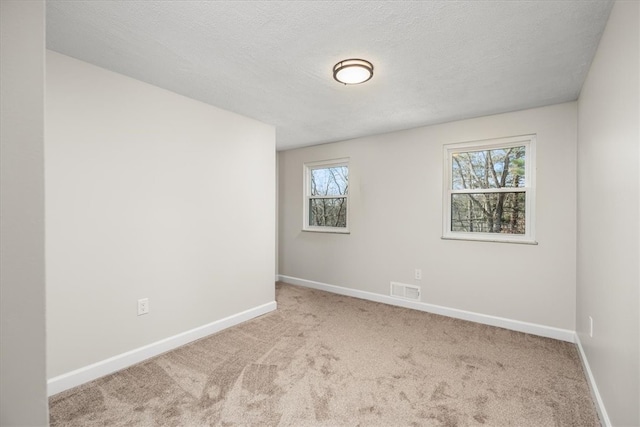 empty room featuring a textured ceiling and light colored carpet