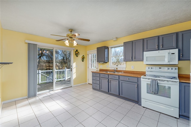 kitchen featuring a textured ceiling, white appliances, ceiling fan, sink, and light tile patterned flooring