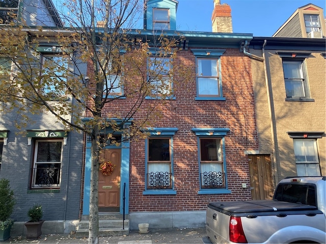 view of front facade with brick siding and a chimney