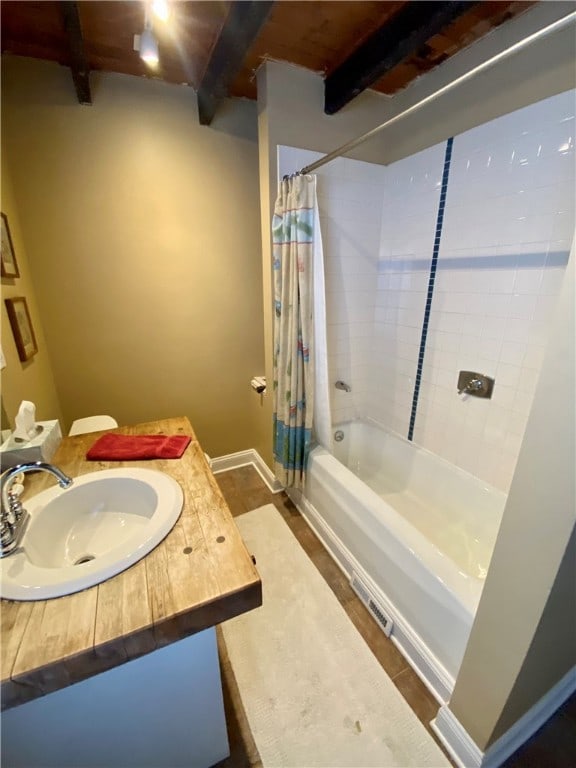 full bath with vanity, baseboards, shower / bath combination with curtain, and beamed ceiling