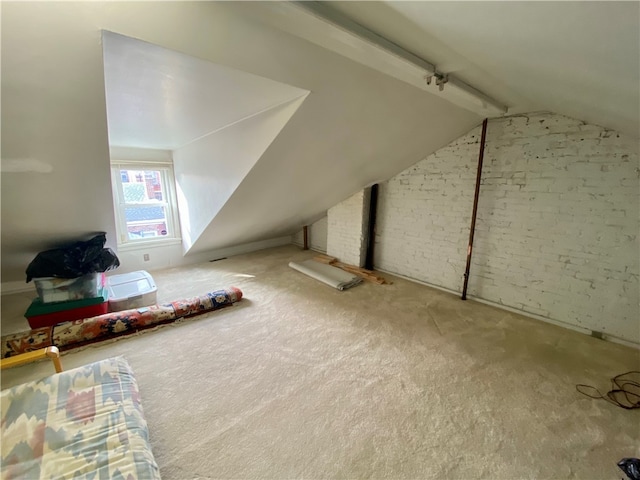 additional living space with carpet, vaulted ceiling with beams, and brick wall