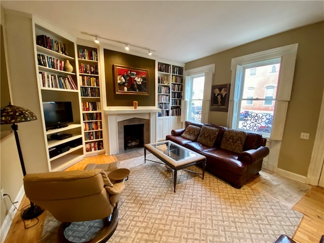 living area featuring a tiled fireplace, wood finished floors, and baseboards