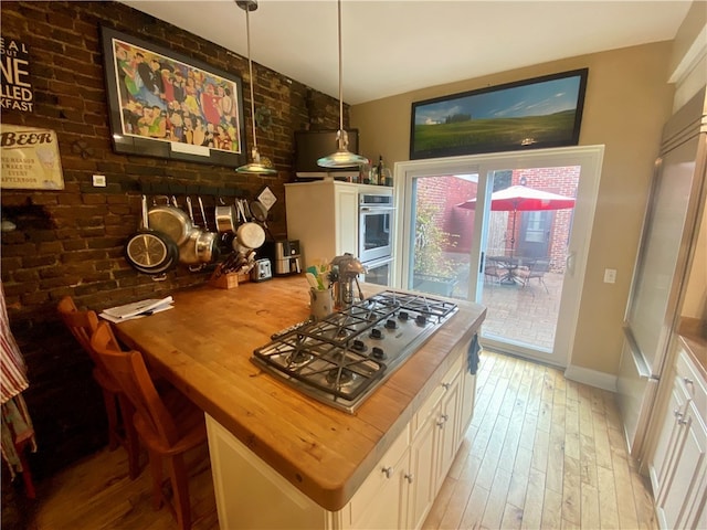 kitchen with white cabinetry, wooden counters, appliances with stainless steel finishes, hanging light fixtures, and light wood finished floors