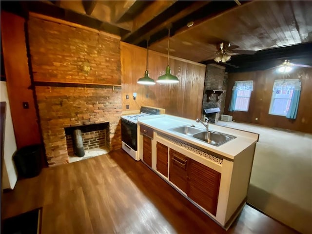 kitchen featuring wooden walls, a fireplace, a sink, white range oven, and a ceiling fan