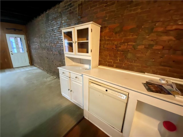 kitchen featuring dishwasher, brick wall, light countertops, and white cabinets