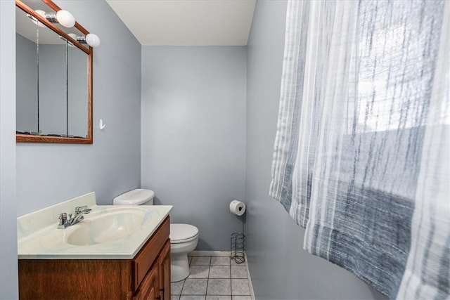 bathroom with toilet, vanity, and tile patterned floors