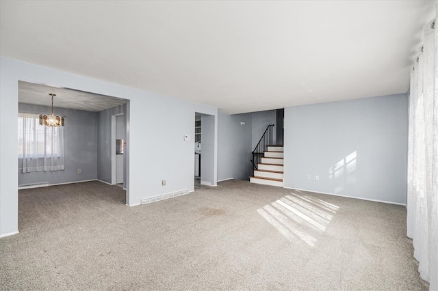 unfurnished living room featuring baseboard heating, carpet floors, and a notable chandelier