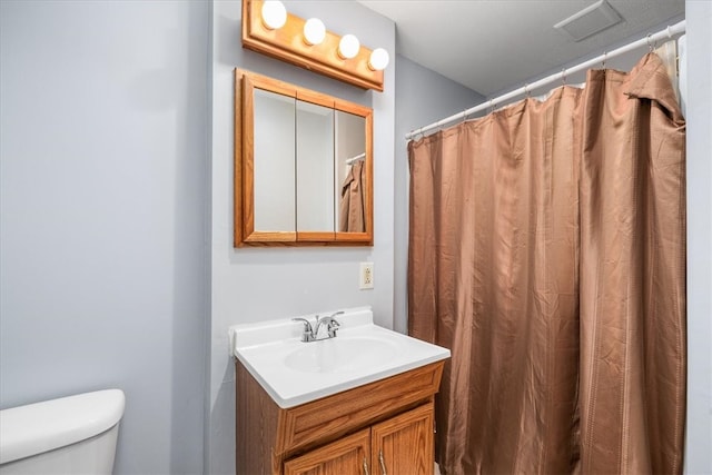 bathroom featuring walk in shower, vanity, and toilet