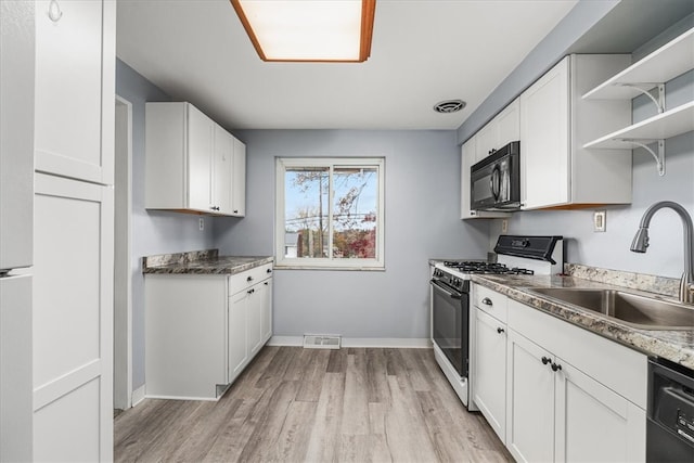 kitchen with white cabinets, sink, black appliances, and light hardwood / wood-style flooring