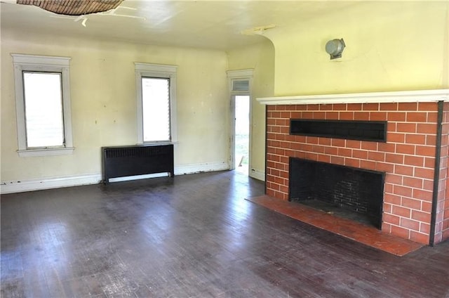 unfurnished living room with a brick fireplace and dark hardwood / wood-style flooring