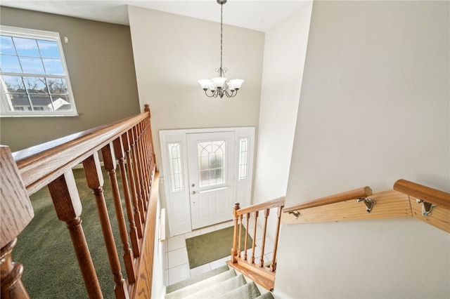 foyer entrance featuring a towering ceiling, tile patterned flooring, and a chandelier