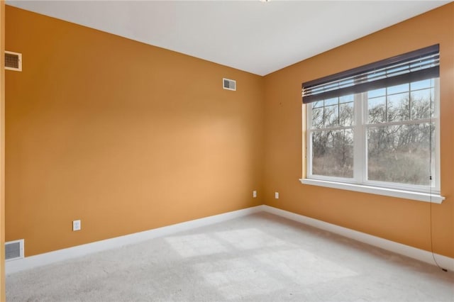 spare room featuring light carpet, visible vents, and baseboards