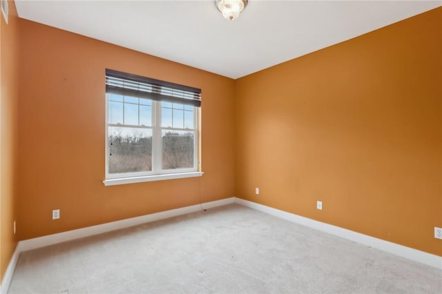 spare room featuring carpet floors and baseboards