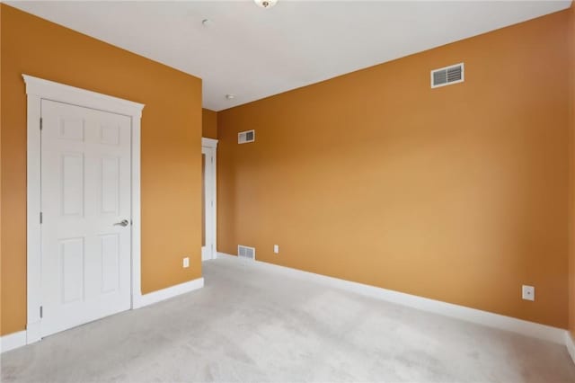 empty room featuring baseboards, visible vents, and light colored carpet