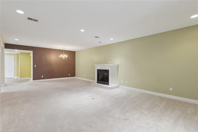 unfurnished living room featuring light carpet, a glass covered fireplace, visible vents, and baseboards