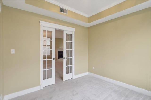 carpeted empty room with visible vents, baseboards, ornamental molding, and french doors