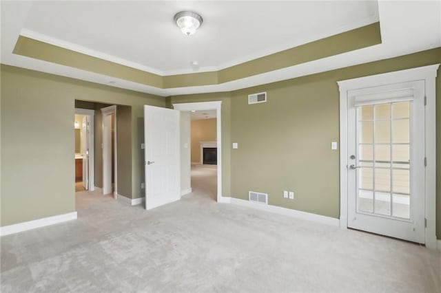 carpeted spare room with a fireplace, visible vents, and a raised ceiling