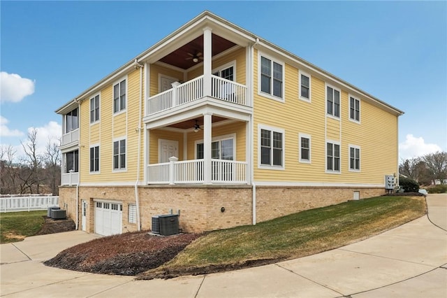 view of side of property featuring central AC unit, an attached garage, a balcony, a ceiling fan, and driveway