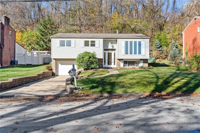 raised ranch with a garage, a front yard, and central air condition unit