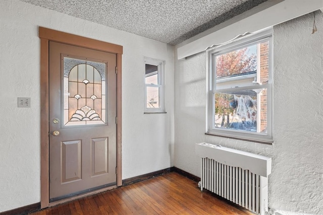 foyer entrance with radiator, a textured ceiling, and dark hardwood / wood-style floors