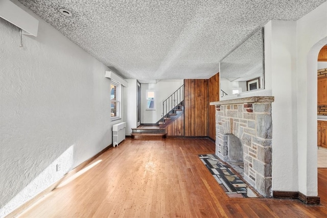 living room with hardwood / wood-style floors, radiator heating unit, a textured ceiling, and a fireplace