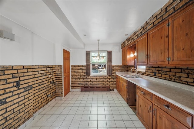 kitchen featuring light tile patterned floors, hanging light fixtures, an inviting chandelier, sink, and brick wall