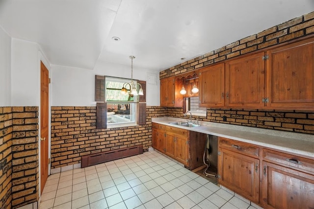 kitchen with pendant lighting, sink, a baseboard radiator, a chandelier, and brick wall