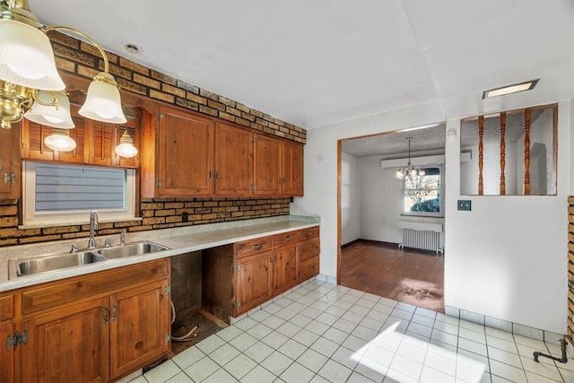 kitchen featuring light hardwood / wood-style floors, sink, radiator, hanging light fixtures, and a notable chandelier