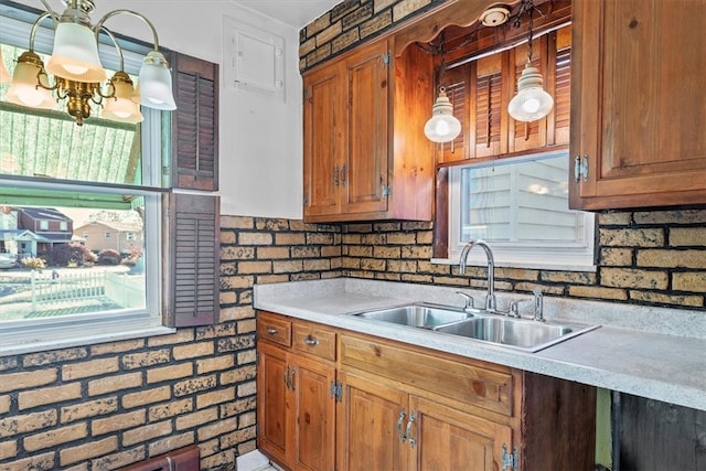 kitchen with plenty of natural light, sink, pendant lighting, and brick wall