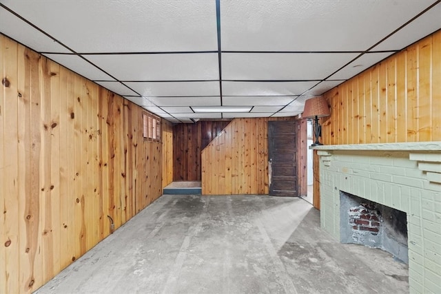 basement featuring a brick fireplace and wood walls