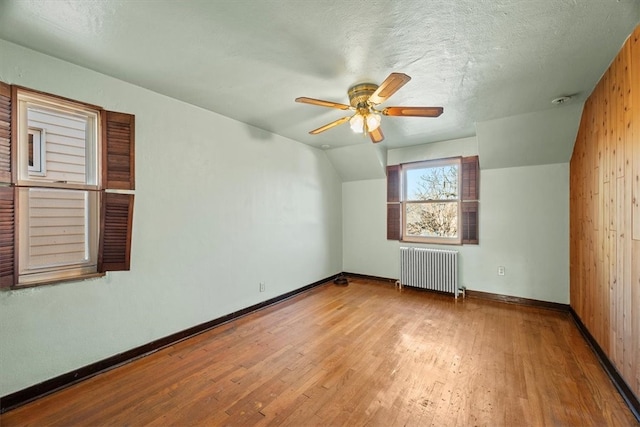 bonus room featuring radiator, ceiling fan, a textured ceiling, light hardwood / wood-style flooring, and vaulted ceiling