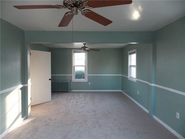 carpeted spare room featuring radiator heating unit and ceiling fan