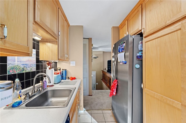 kitchen featuring tasteful backsplash, light tile patterned flooring, stainless steel fridge, light brown cabinetry, and sink