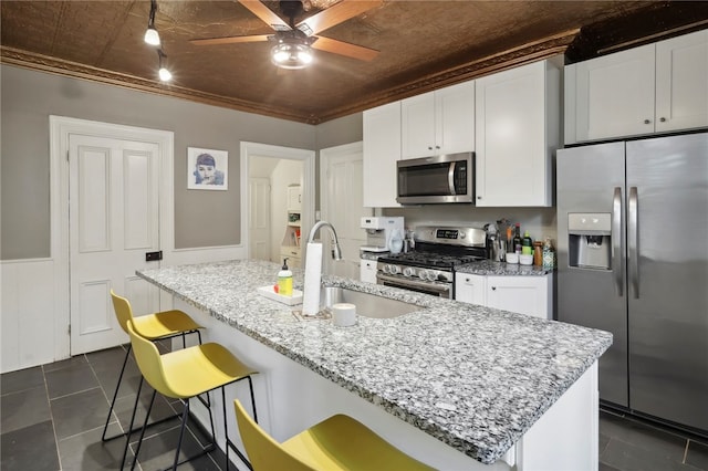 kitchen featuring a kitchen breakfast bar, white cabinetry, stainless steel appliances, and light stone counters