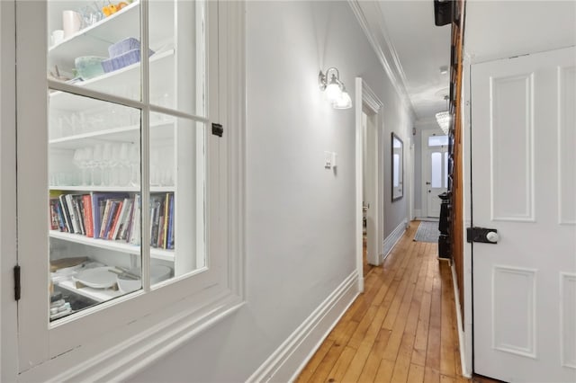 hall with light hardwood / wood-style floors and crown molding