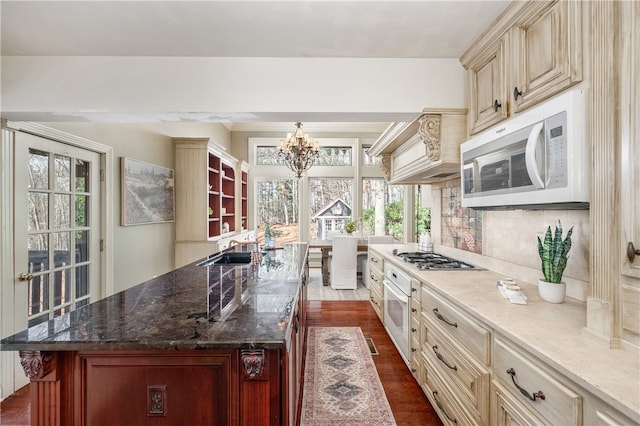 kitchen featuring cream cabinets, a chandelier, wood-type flooring, white appliances, and custom range hood