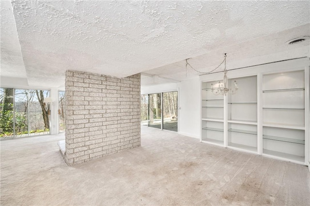 carpeted spare room featuring a textured ceiling and a notable chandelier