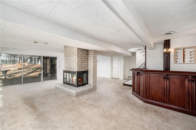 unfurnished living room with a textured ceiling, light carpet, and a brick fireplace