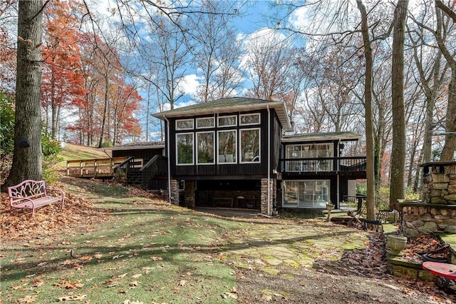 back of house featuring a sunroom, a yard, and a wooden deck