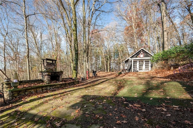 view of yard featuring an outdoor stone fireplace and an outbuilding