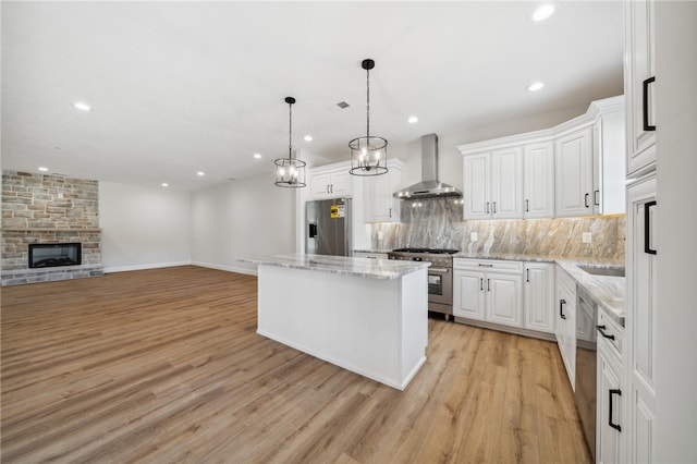 kitchen with a kitchen island, white cabinets, wall chimney exhaust hood, and stainless steel appliances