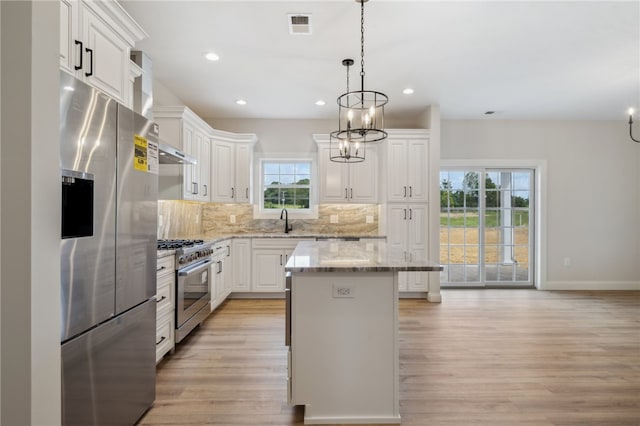 kitchen featuring a center island, white cabinetry, appliances with stainless steel finishes, pendant lighting, and light hardwood / wood-style flooring